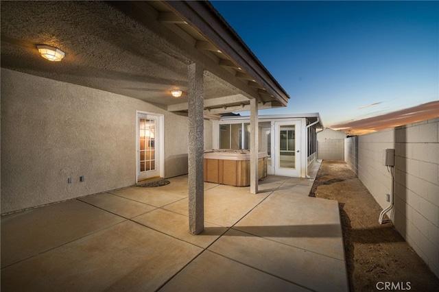 patio terrace at dusk featuring a hot tub