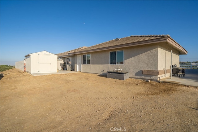 back of property with a storage unit and a patio