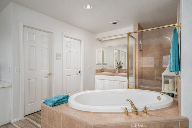 bathroom with hardwood / wood-style floors, vanity, and shower with separate bathtub