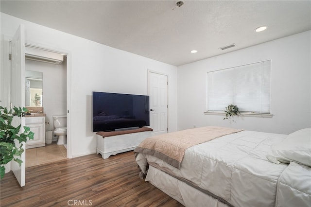 bedroom with ensuite bathroom and dark hardwood / wood-style flooring