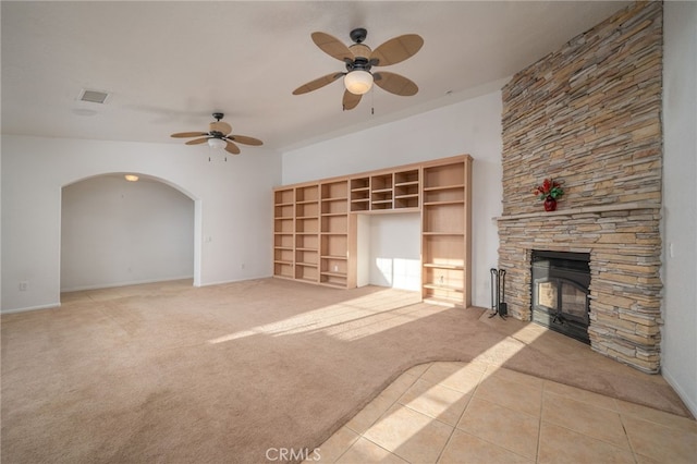 unfurnished living room with ceiling fan, light tile patterned flooring, and a fireplace