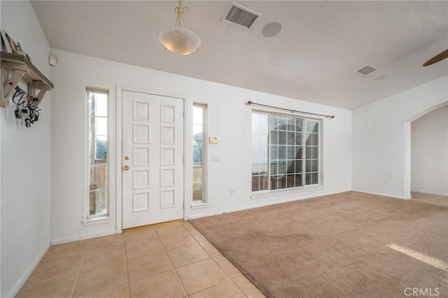 foyer featuring light carpet and a textured ceiling