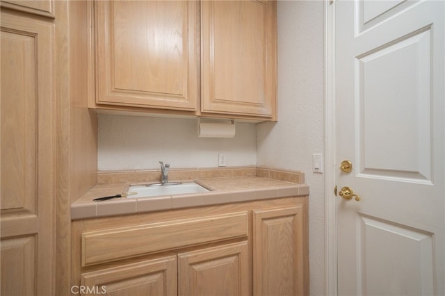 kitchen with tile countertops, sink, and light brown cabinetry