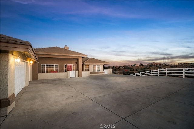 patio terrace at dusk featuring a garage