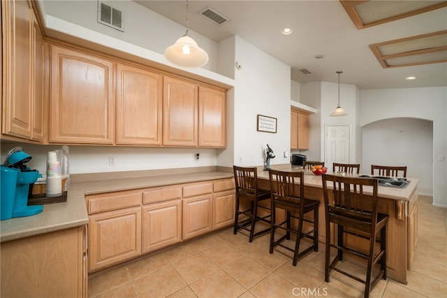 kitchen featuring a breakfast bar area, light brown cabinetry, light tile patterned floors, and pendant lighting