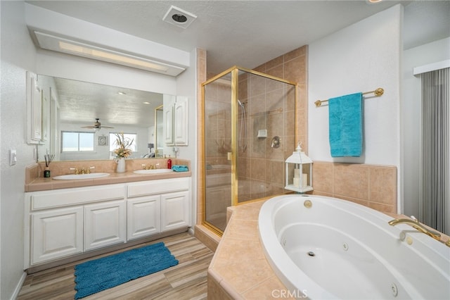 bathroom with ceiling fan, wood-type flooring, a textured ceiling, vanity, and independent shower and bath