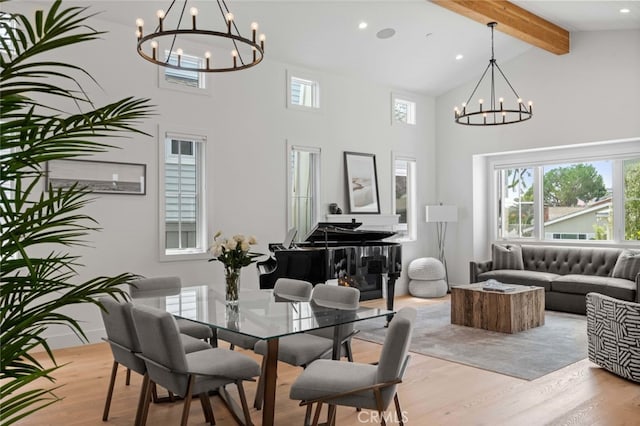 dining area with an inviting chandelier, beamed ceiling, high vaulted ceiling, and light hardwood / wood-style floors