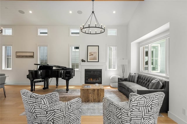 living room featuring a chandelier, light wood-type flooring, and a towering ceiling