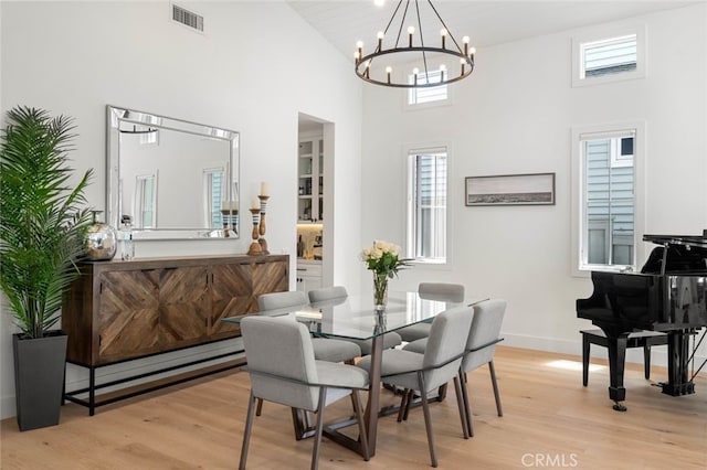 dining area featuring a high ceiling, light hardwood / wood-style flooring, and a notable chandelier