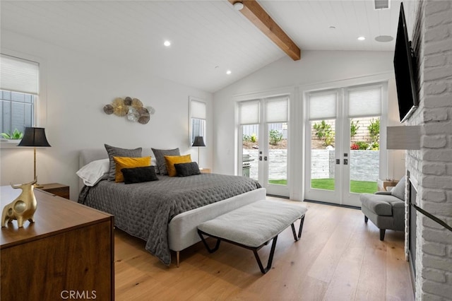 bedroom with access to exterior, a stone fireplace, vaulted ceiling with beams, light hardwood / wood-style floors, and french doors