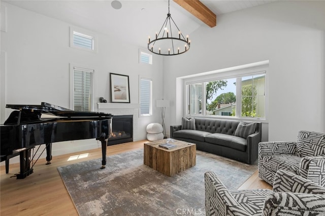 living room with beam ceiling, high vaulted ceiling, wood-type flooring, and an inviting chandelier