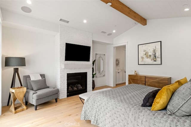 bedroom with light hardwood / wood-style floors, lofted ceiling with beams, and a fireplace