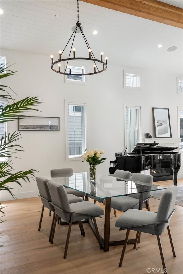 dining room with light hardwood / wood-style flooring, a notable chandelier, and a high ceiling