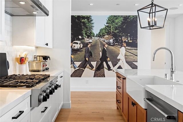 kitchen with light hardwood / wood-style flooring, wall chimney exhaust hood, white cabinets, and appliances with stainless steel finishes