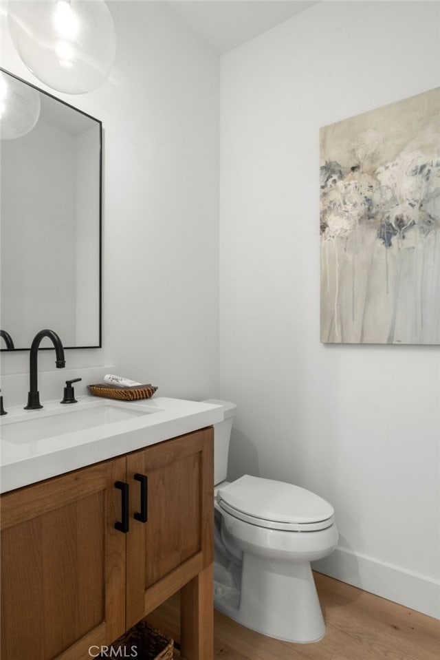 bathroom featuring toilet, hardwood / wood-style floors, and vanity