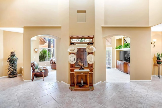 entrance foyer with light tile patterned floors, arched walkways, and a towering ceiling
