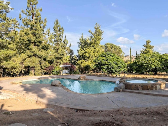 pool with an in ground hot tub and a patio area