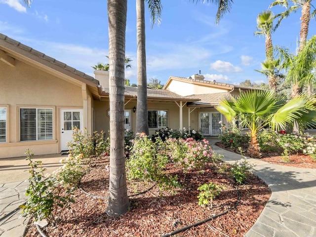 view of front of property with a tiled roof, stucco siding, and french doors