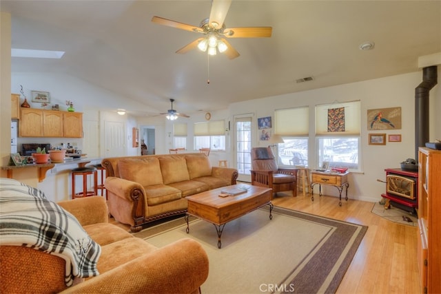 living room with light hardwood / wood-style floors, a wood stove, and a wealth of natural light