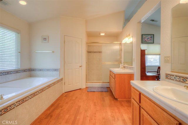 bathroom with vanity, a healthy amount of sunlight, vaulted ceiling, and separate shower and tub