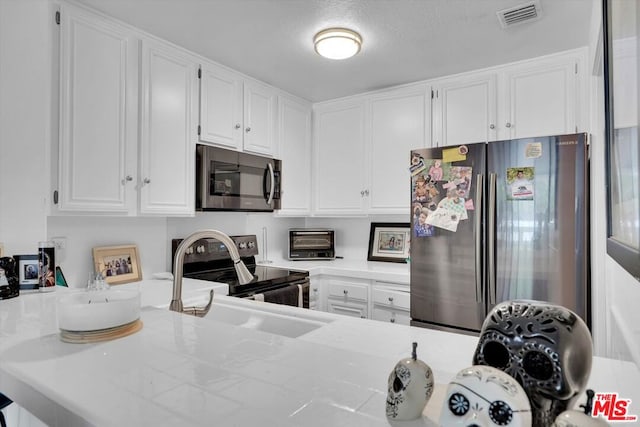 kitchen with appliances with stainless steel finishes, white cabinets, and sink