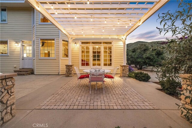 patio terrace at dusk with a mountain view and a pergola