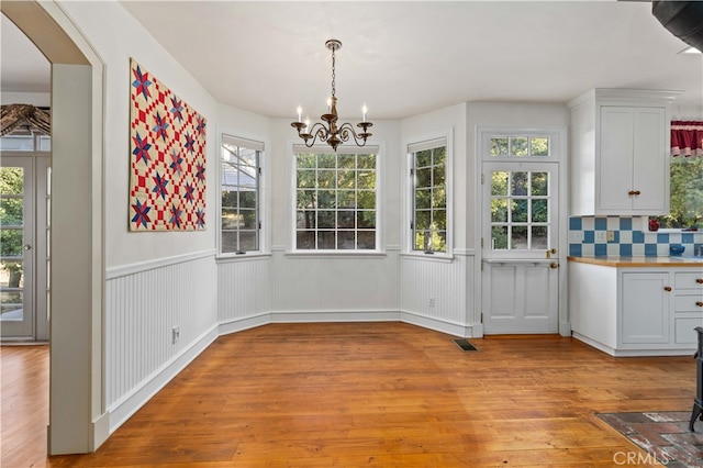 unfurnished dining area featuring light hardwood / wood-style floors and a chandelier