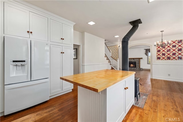 kitchen featuring white cabinetry, white refrigerator with ice dispenser, light wood-type flooring, and butcher block counters