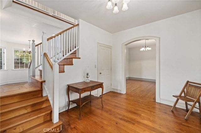 staircase with wood-type flooring and a chandelier