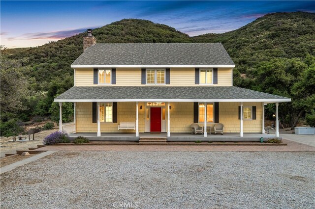 farmhouse inspired home with covered porch and a mountain view