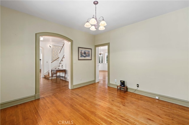 empty room with light hardwood / wood-style flooring and a notable chandelier