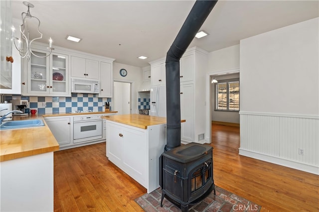 kitchen with backsplash, sink, white cabinetry, butcher block countertops, and white appliances