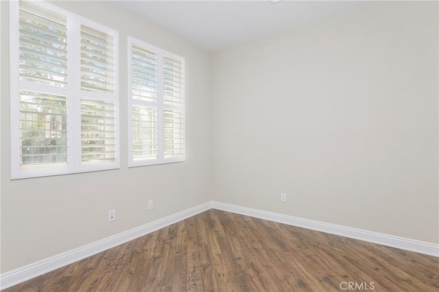 unfurnished room with baseboards and wood finished floors