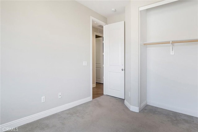 unfurnished bedroom with a closet, light carpet, and baseboards