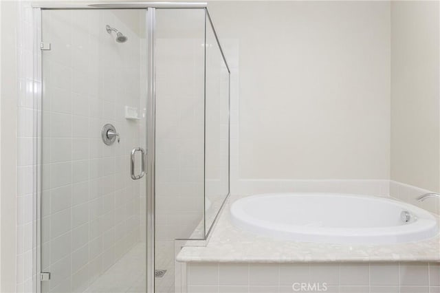 bathroom with a stall shower and a garden tub