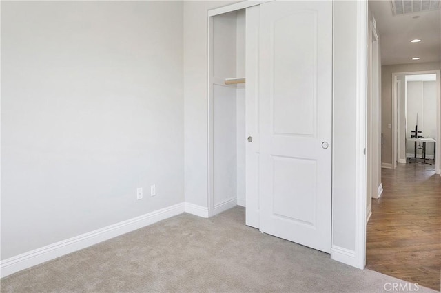 unfurnished bedroom featuring light carpet and a closet