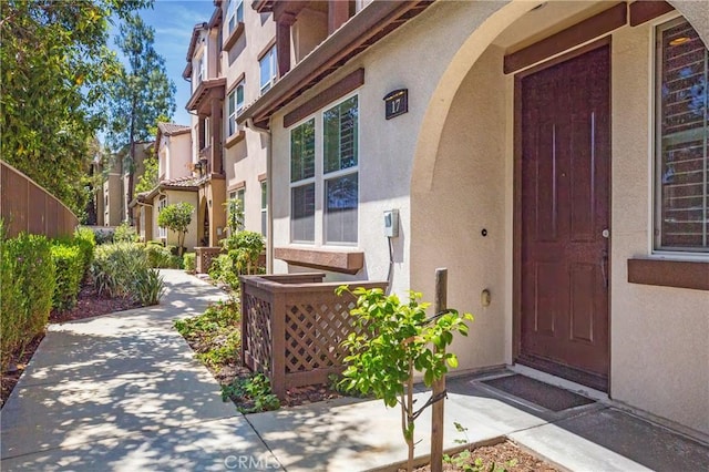 doorway to property with fence and stucco siding