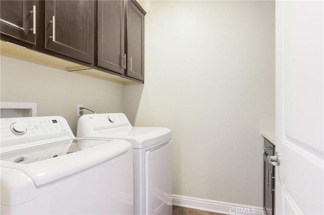 laundry room featuring separate washer and dryer, cabinet space, and baseboards