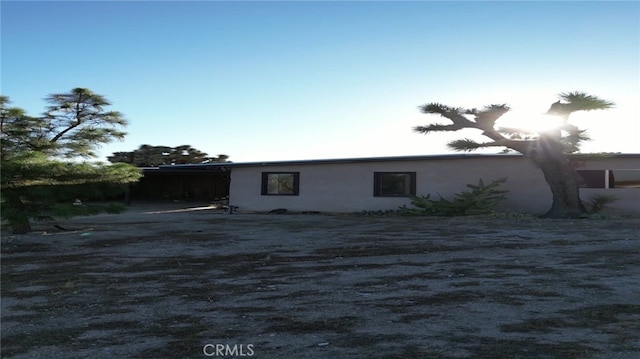 back of property with a carport and stucco siding