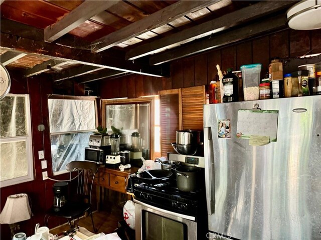 kitchen with appliances with stainless steel finishes, wood walls, and beamed ceiling