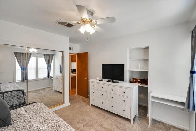 bedroom featuring visible vents, light carpet, a closet, and a ceiling fan