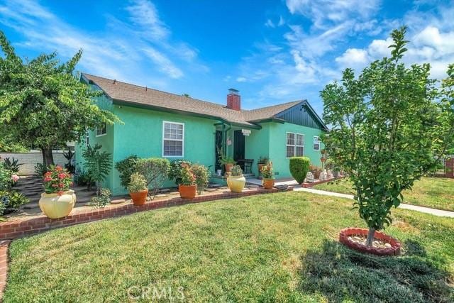 back of property with a lawn, a chimney, and stucco siding