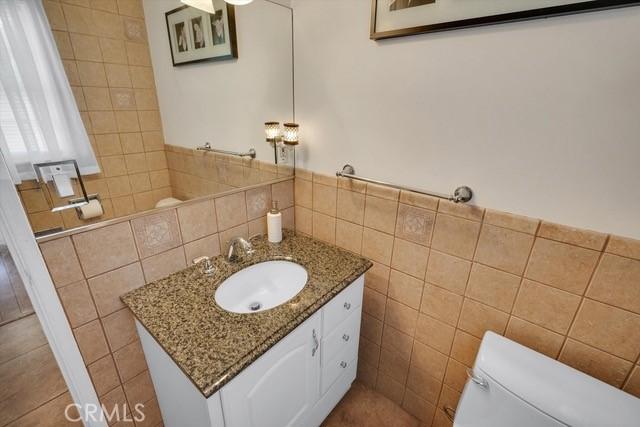 bathroom featuring vanity, tile walls, and toilet