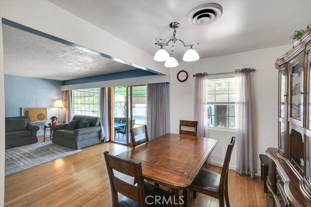 dining area with a wealth of natural light, visible vents, and light wood finished floors