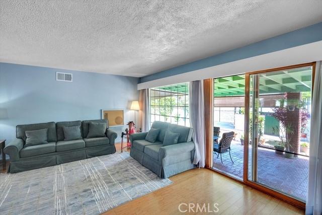 living area featuring visible vents, a textured ceiling, and wood finished floors