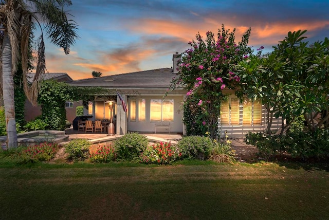 back house at dusk with a yard and a patio