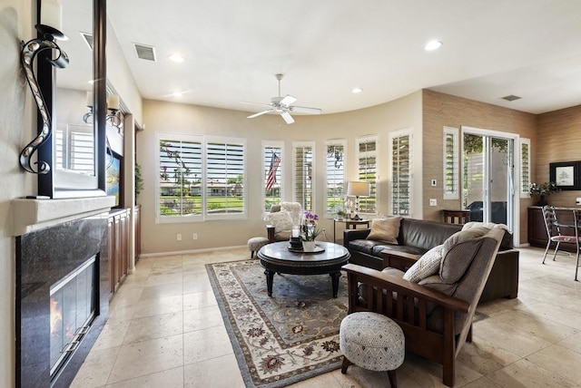 living room featuring a premium fireplace, a healthy amount of sunlight, and ceiling fan