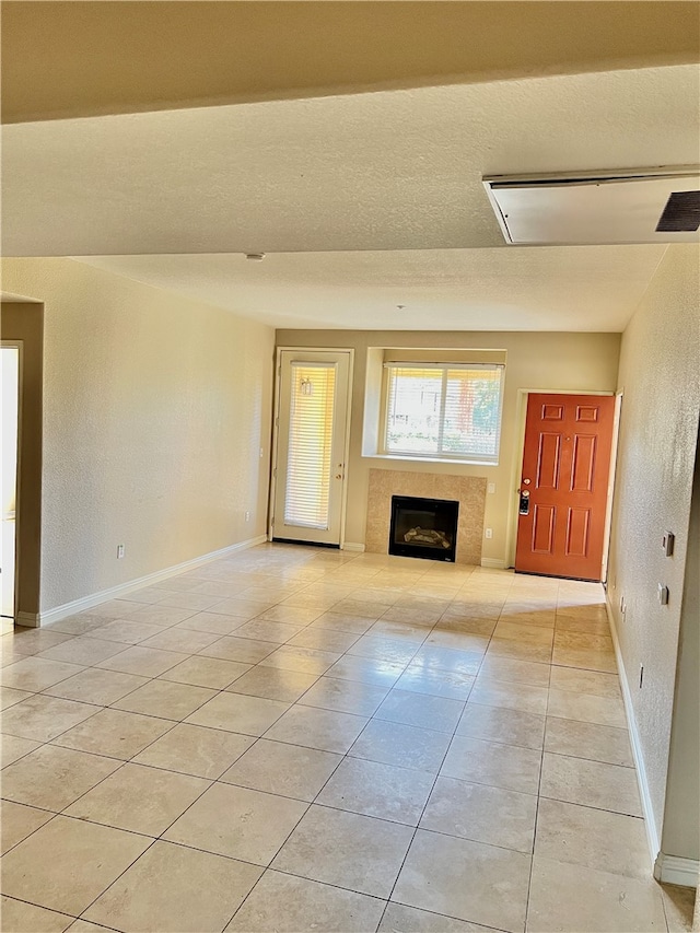 unfurnished living room with light tile patterned flooring and a tile fireplace