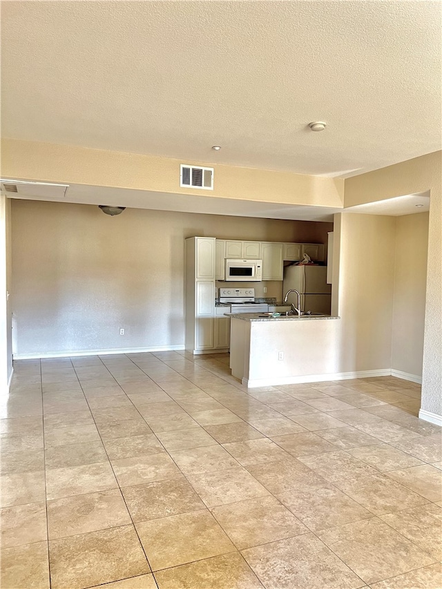 kitchen featuring white cabinetry, kitchen peninsula, a textured ceiling, and white appliances