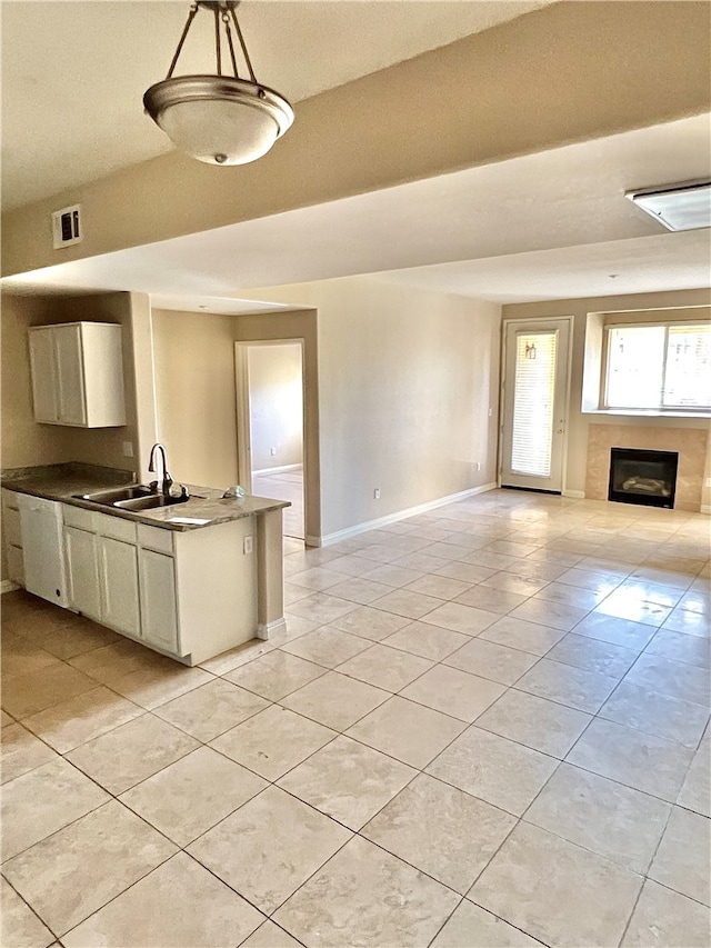 kitchen with sink, light tile patterned flooring, kitchen peninsula, and decorative light fixtures